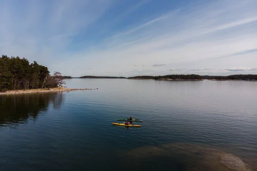 Drönarbild av två personer som paddlar kajak i skärgården