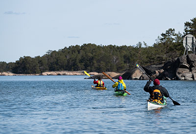The persons kajaking close to the shore of an island