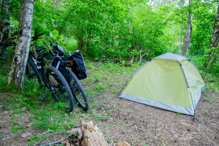 Två cyklar och ett grönt tält på en campingplats i Naawa Nature