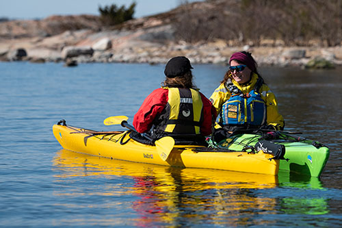 Two girls speaking on their kayaks